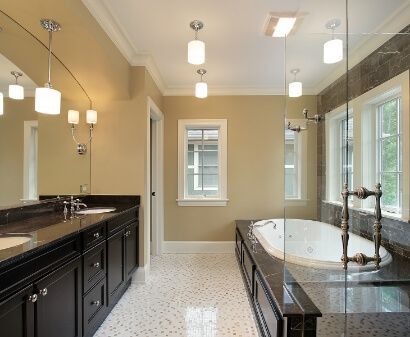 Elegant bathroom with dark cabinets, a white bathtub, and multiple pendant lights.