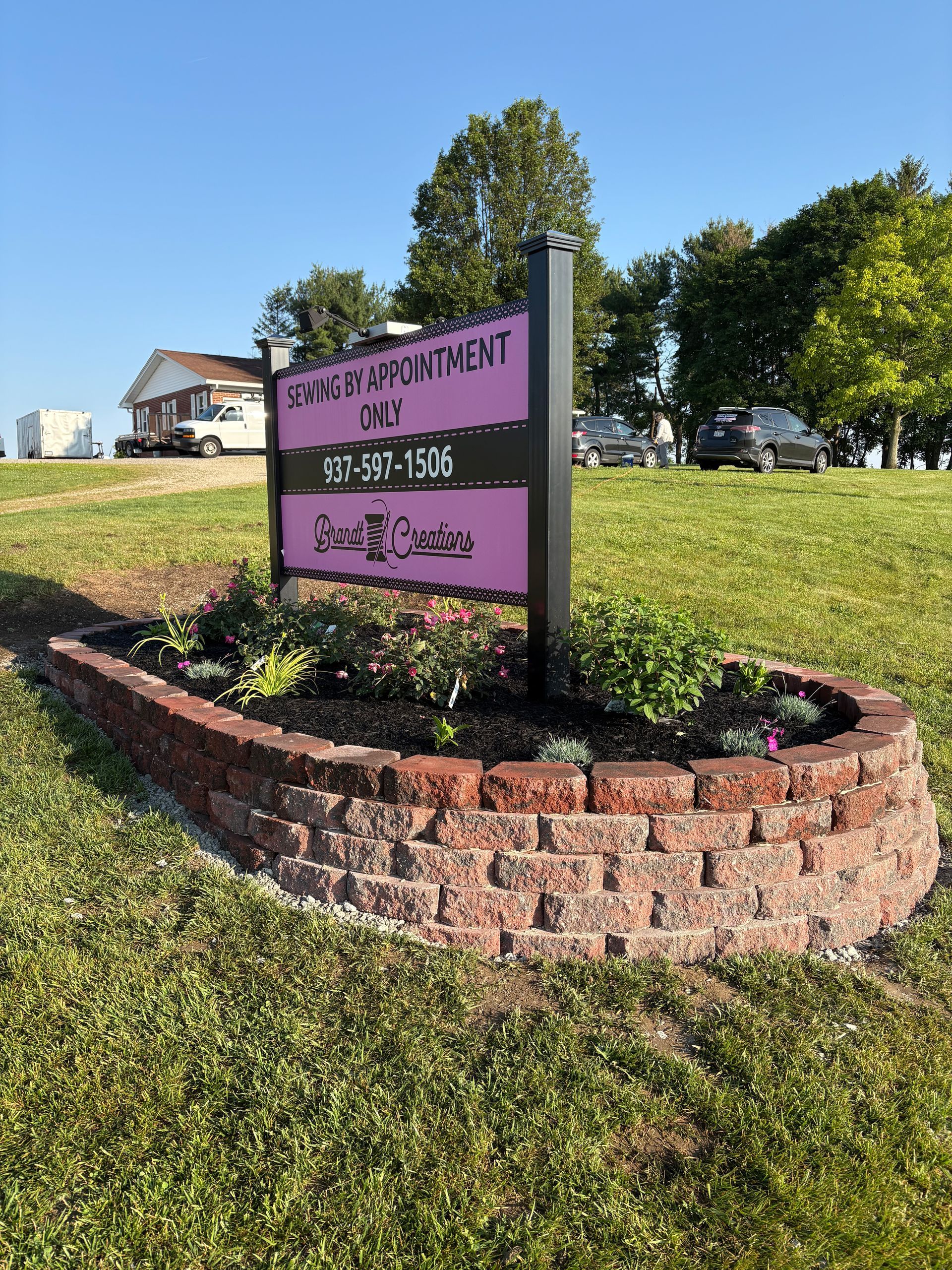 Sign for The Town Apartment with landscaping, pink and black.