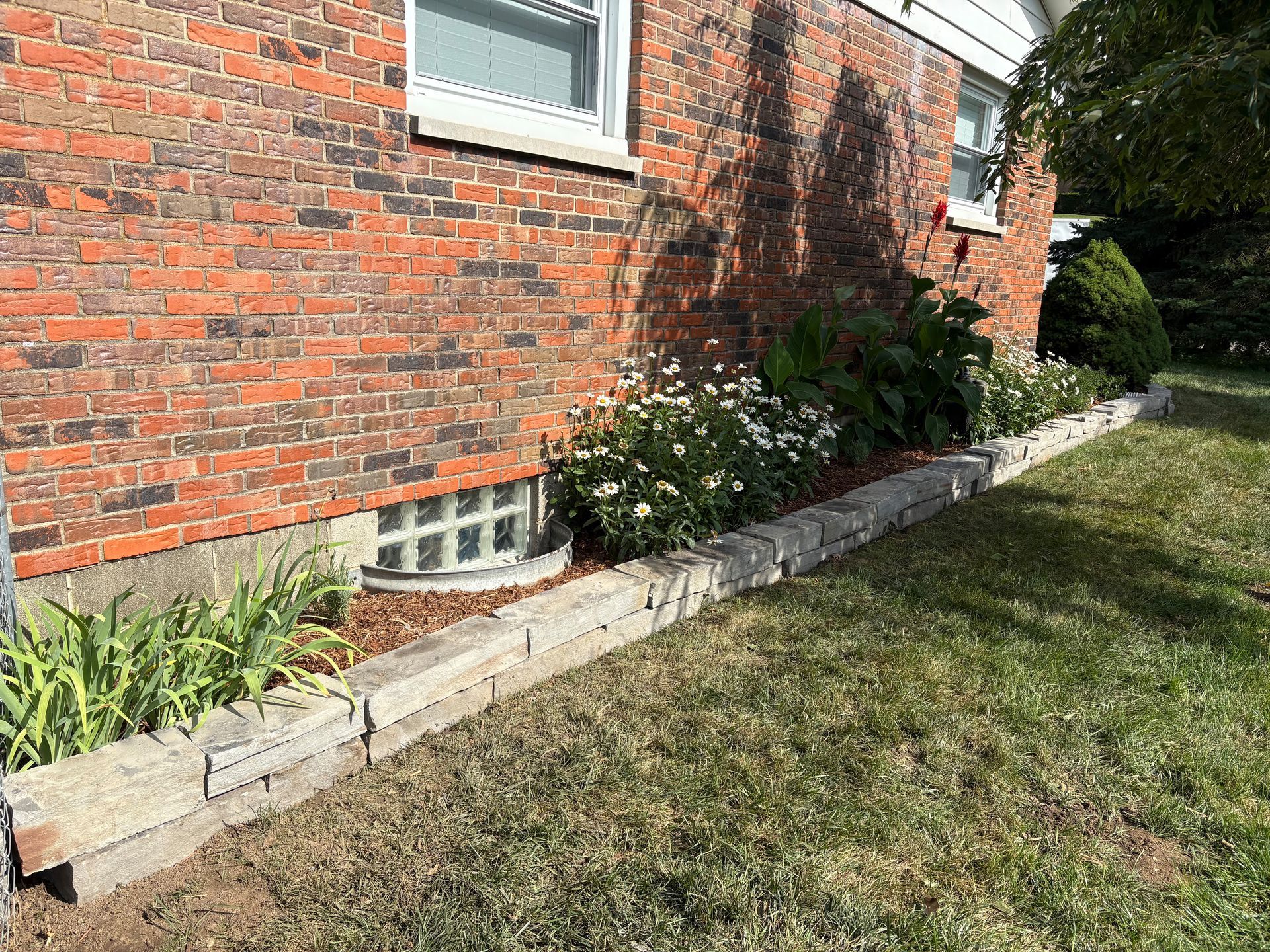 Brick house with a flower bed bordered by concrete blocks.