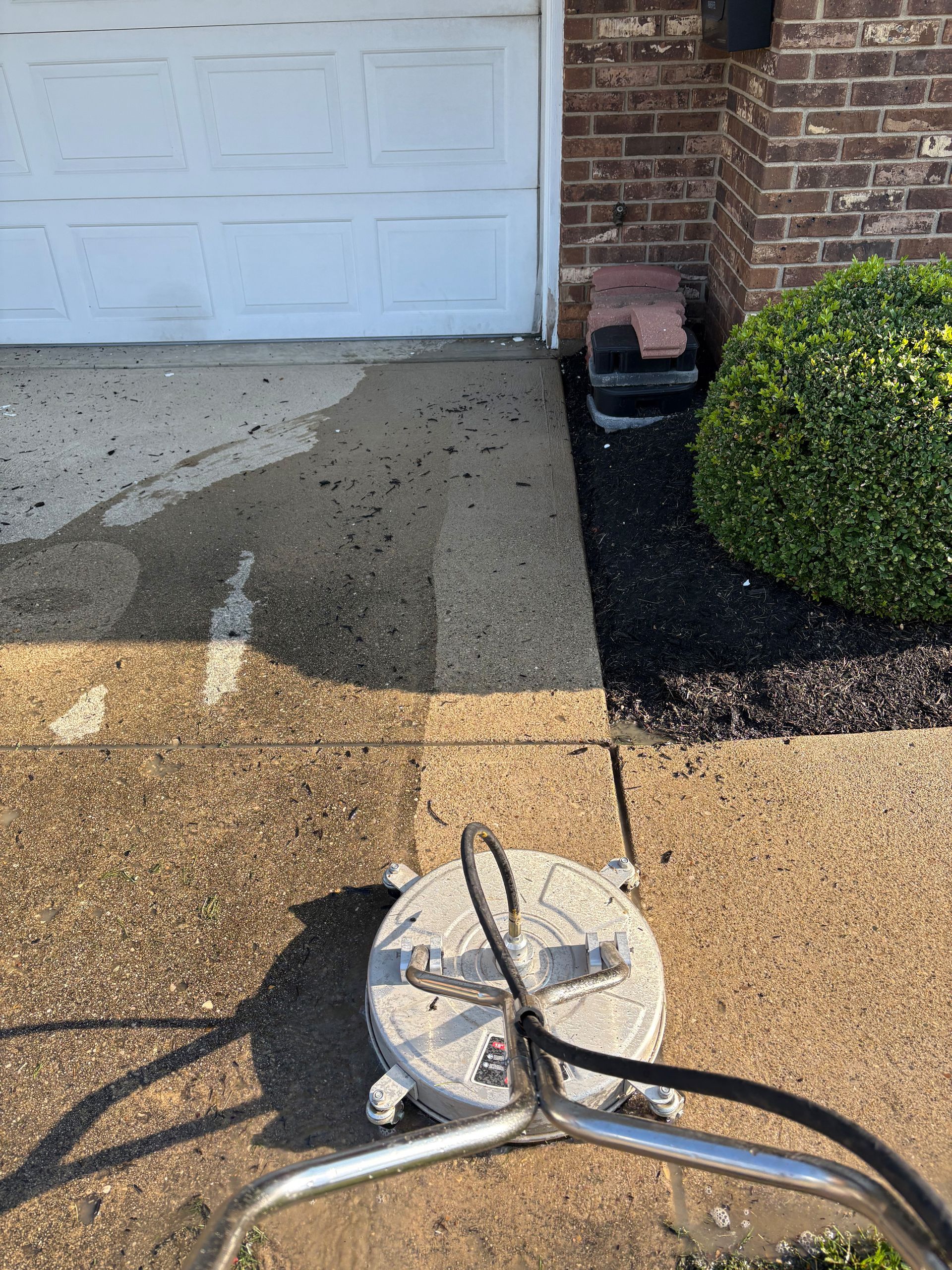 Power washer cleaning a concrete driveway, showing the before and after cleaning.