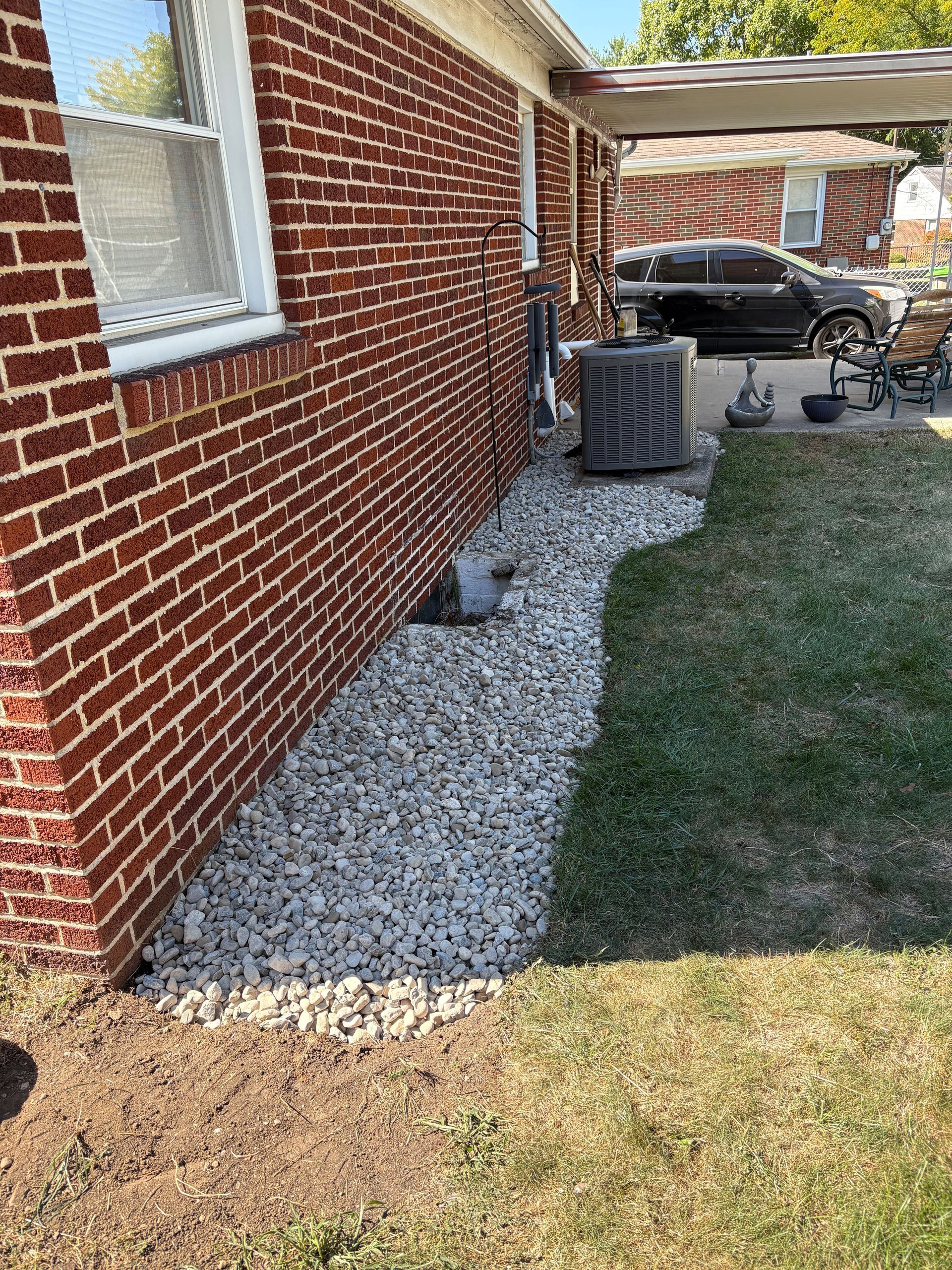 Brick house with white gravel landscaping next to the wall. Air conditioner visible.
