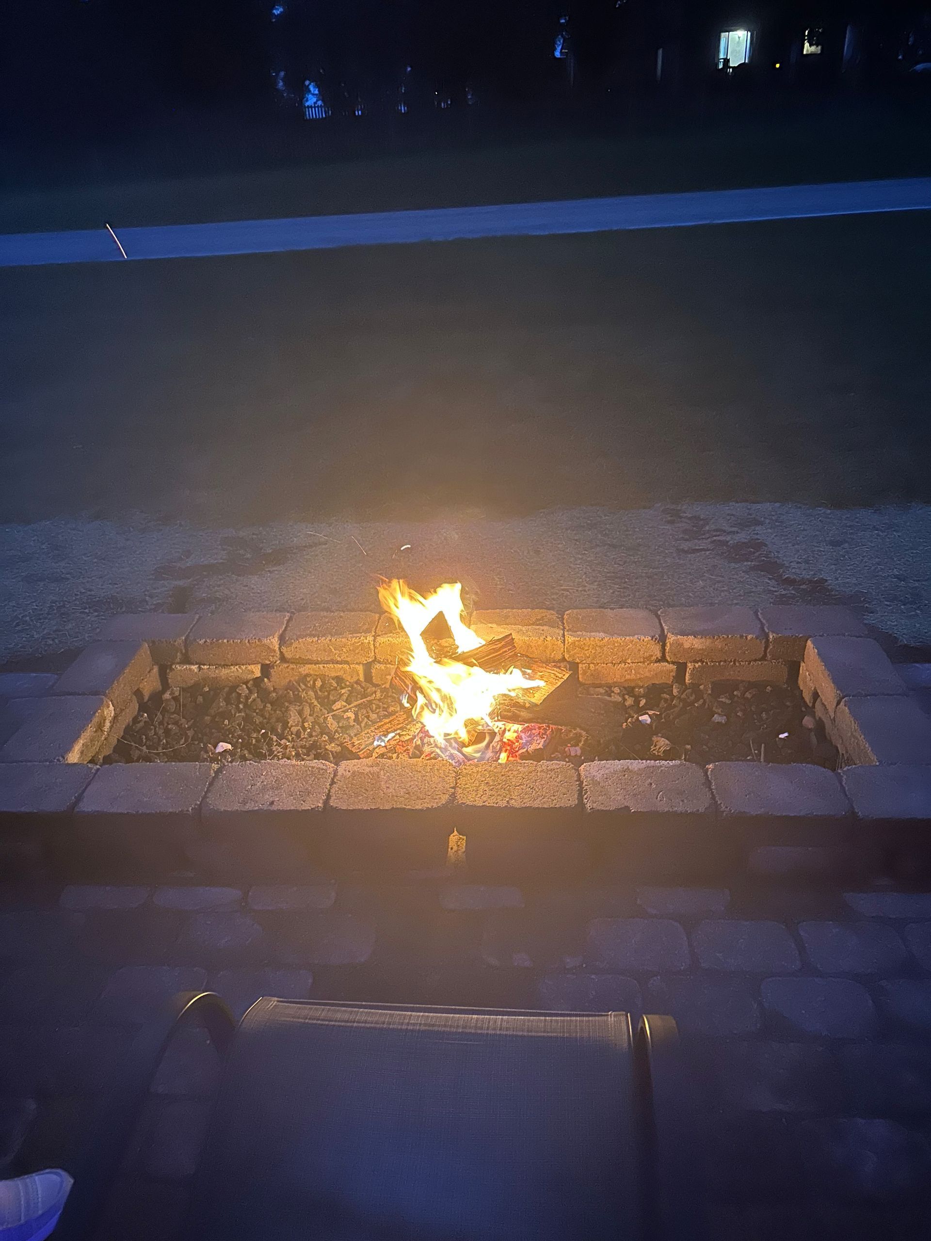 Fire burning in a brick fire pit at night.