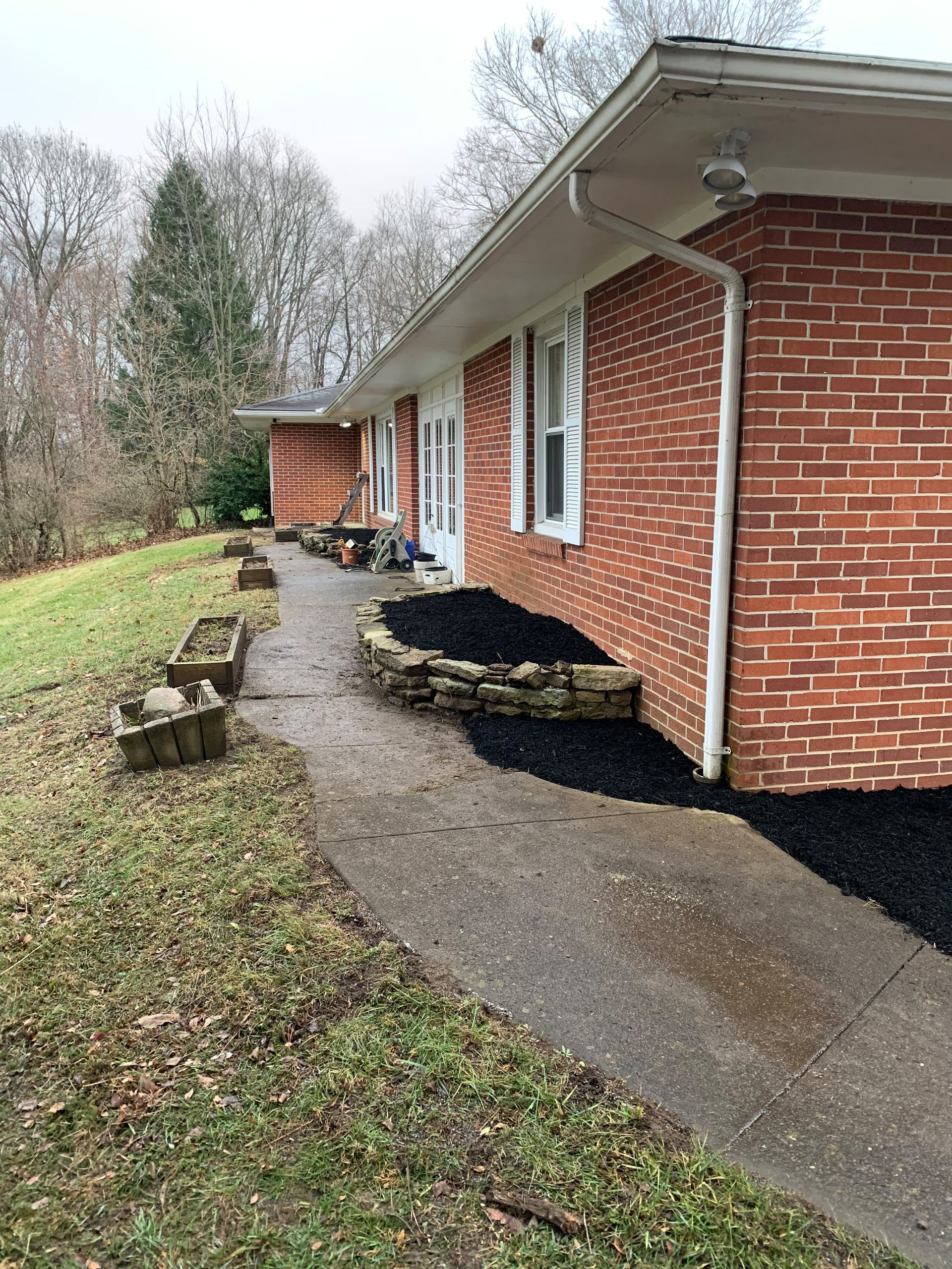 Brick house with pathway and flowerbeds. Overcast day.