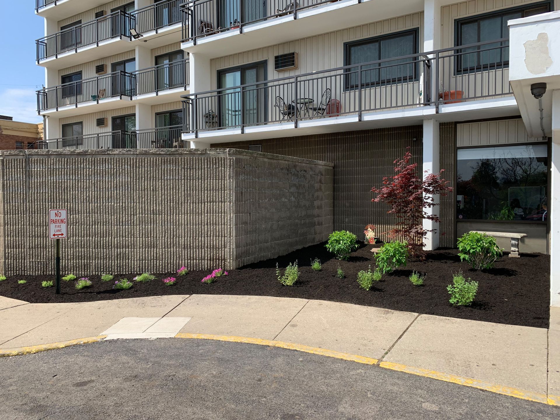 Exterior of a multi-story building with balconies and landscaping in front.