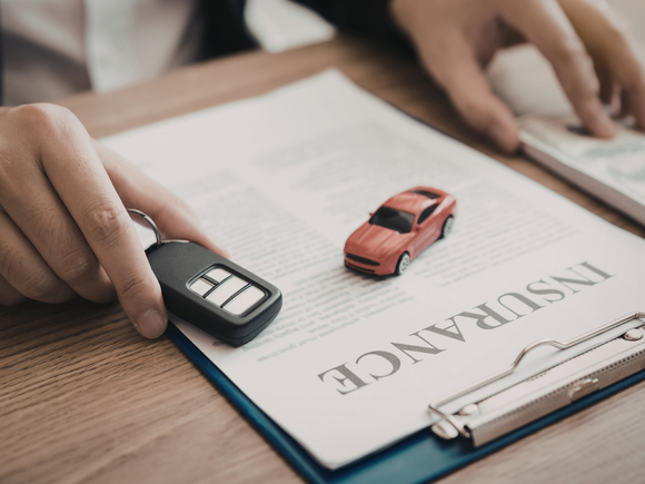 Car keys and a miniature red car placed on insurance documents, symbolizing coverage from a home and auto insurance broker service in Maricopa, AZ