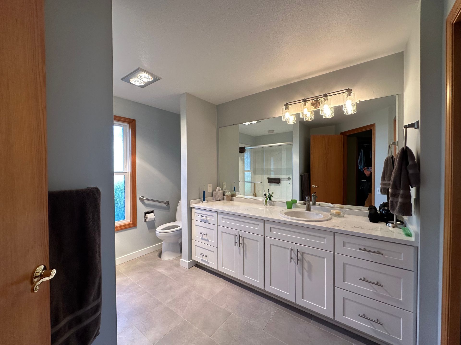A bathroom with two sinks , a toilet , and a large mirror.