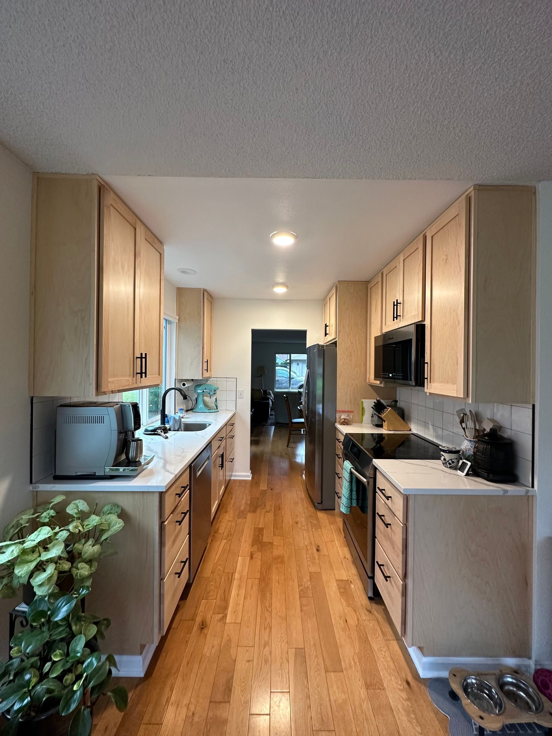 A long kitchen with wooden cabinets and hardwood floors
