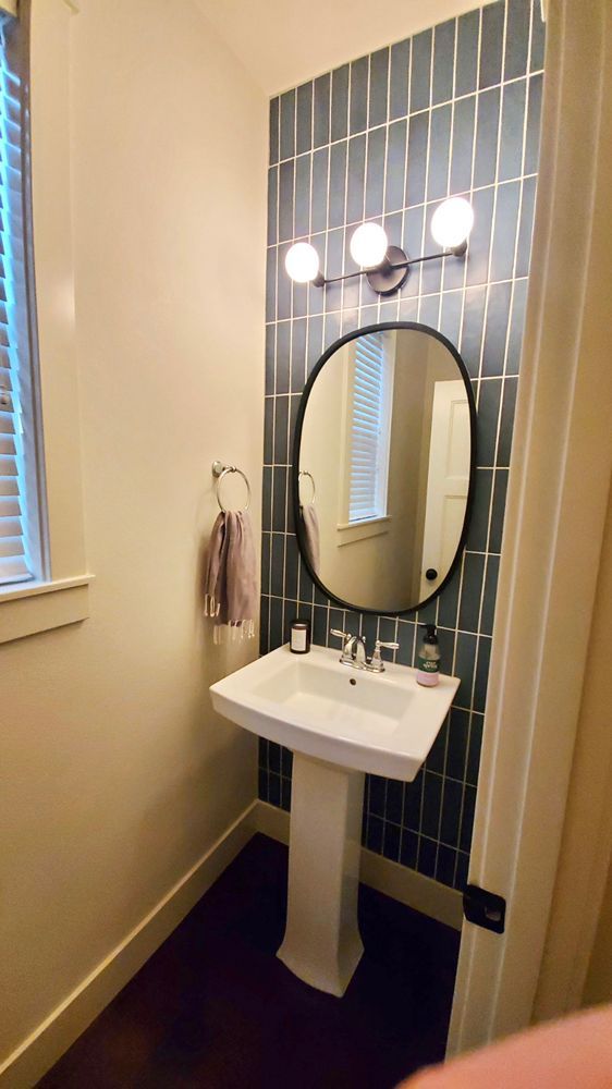A bathroom with a sink , mirror and window.