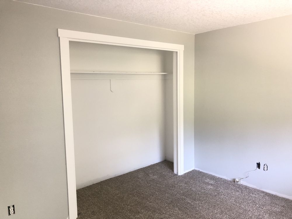 An empty bedroom with a closet and a shelf.