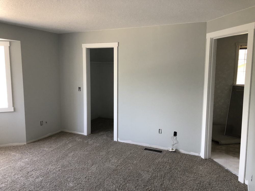 An empty room with a carpeted floor and gray walls.