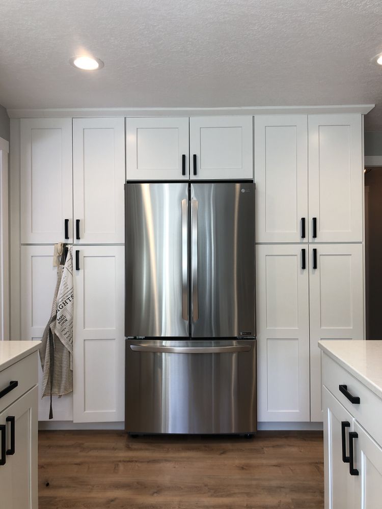 A kitchen with white cabinets and a stainless steel refrigerator