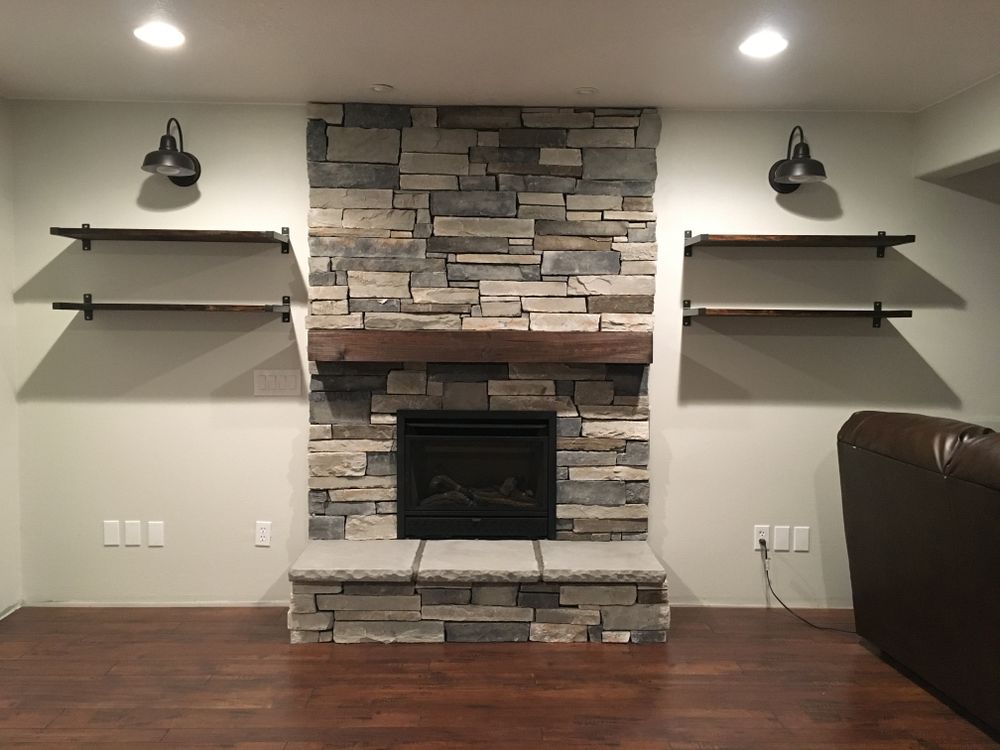 A living room with a stone fireplace and shelves