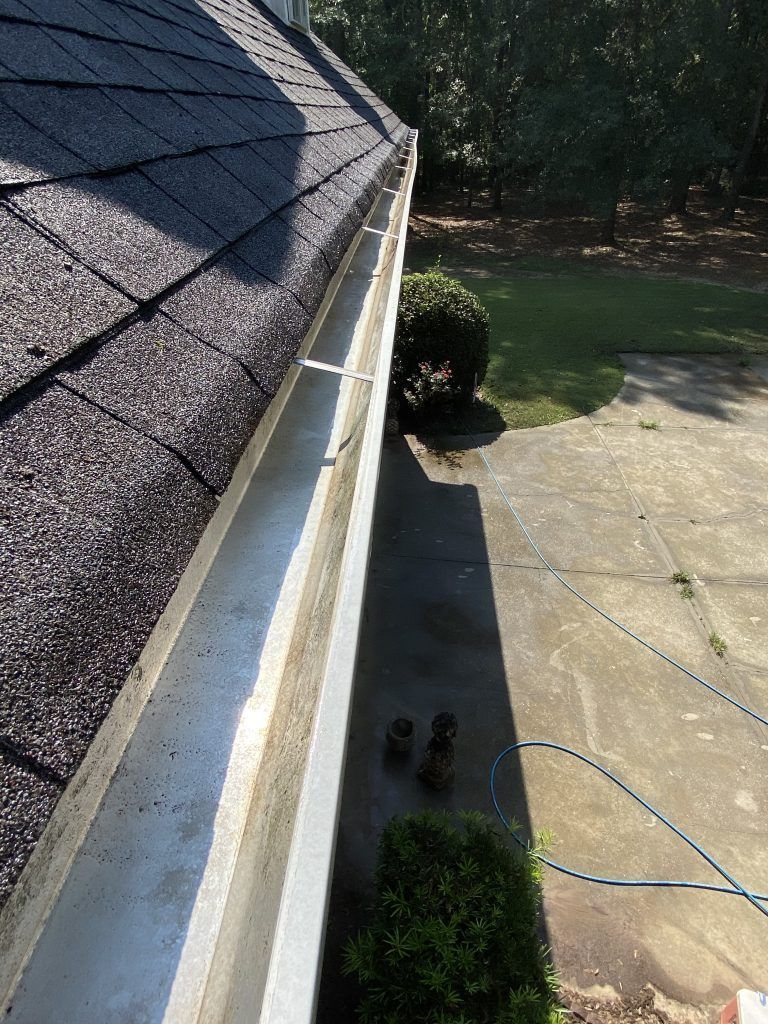 A gutter on the side of a house with a hose attached to it.