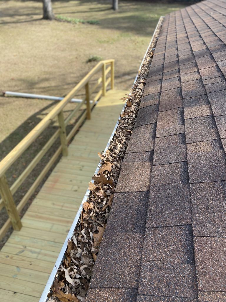 A gutter filled with leaves on a roof next to a ramp.