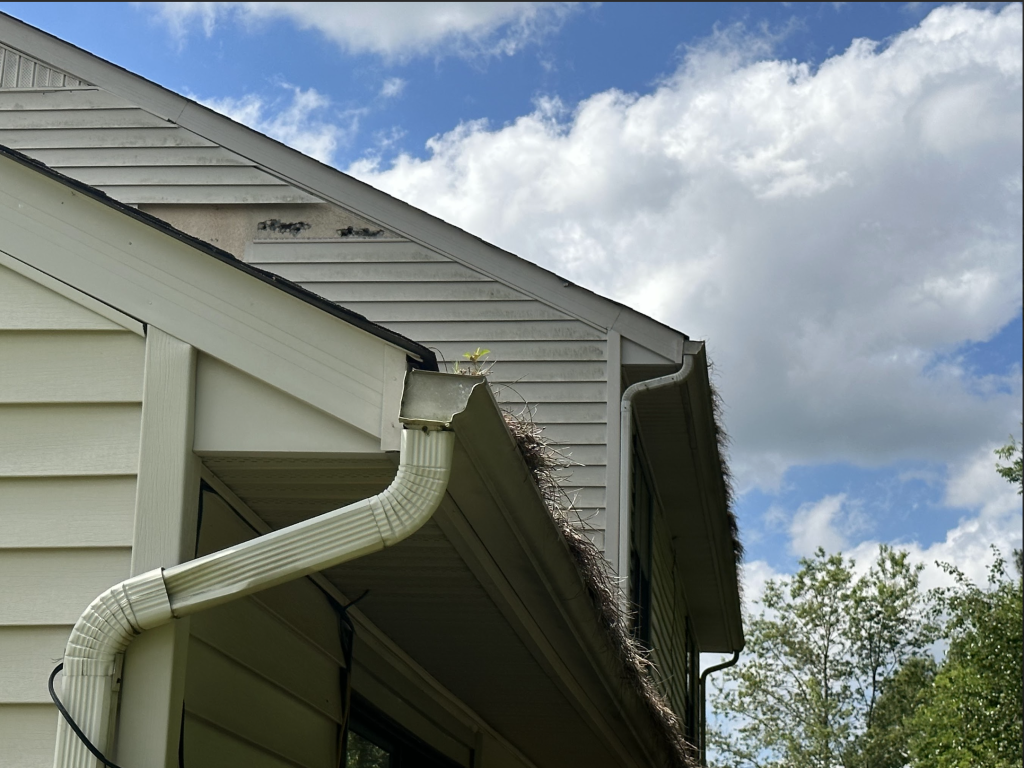 A gutter on the side of a house with a blue sky in the background