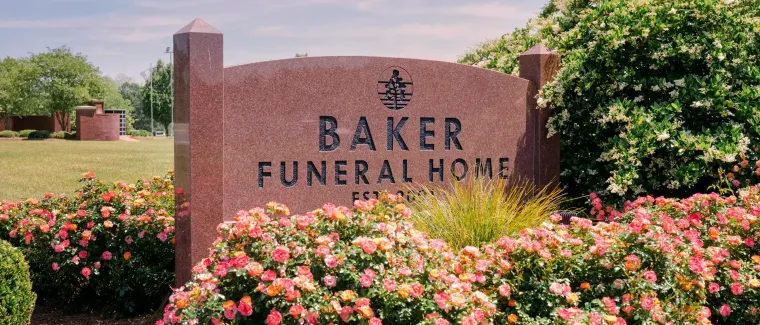 A large brick building with a sign in front of it that says baker funeral home.