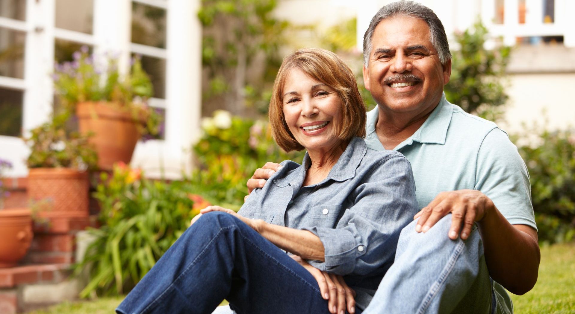 an elderly couple is sitting in the leaves under a tree .