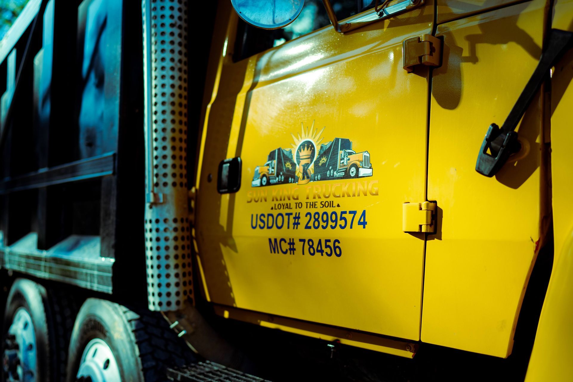 A yellow dump truck is parked on the side of the road