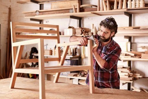 un uomo lavora una sedia di legno nella sua bottega