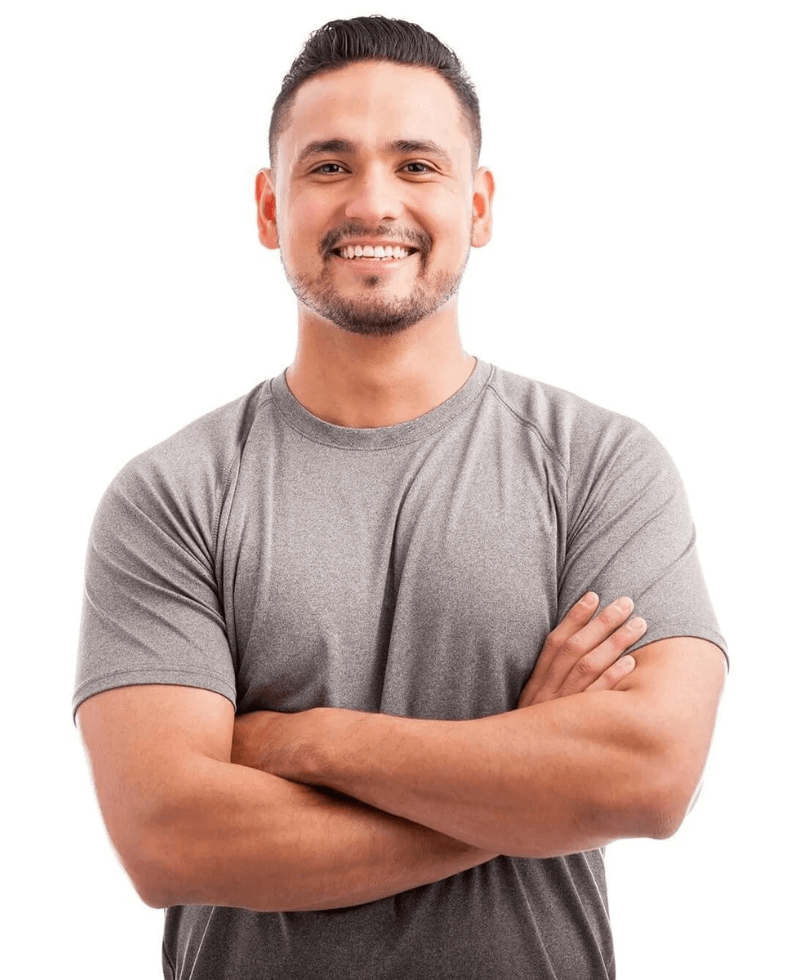 A man in a grey shirt is smiling with his arms crossed