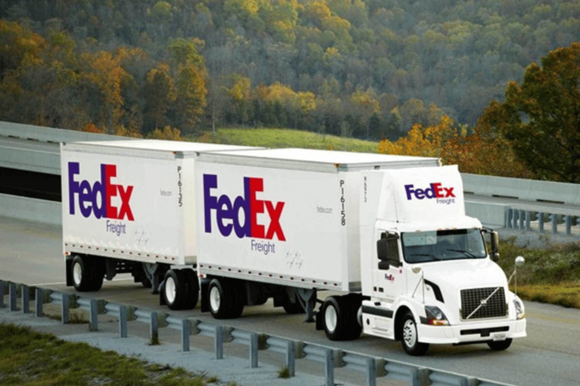 Two fedex trucks are driving down a highway