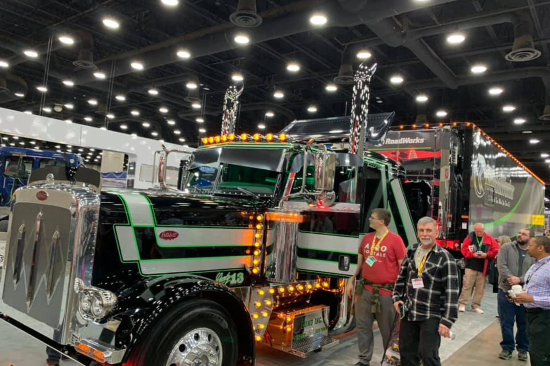 A group of men are standing around a large truck at Mid America Truck Show.