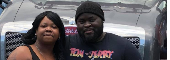 A man and a woman are posing for a picture in front of a truck.