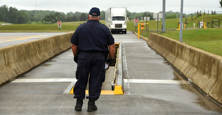 DOT enforcement officer standing in front of a scale house, awaiting inspection of a semi-truck for 