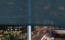 A window with a blue blind on it and a christmas tree in the background.