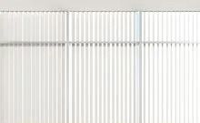 A close up of a white vertical blind on a window.