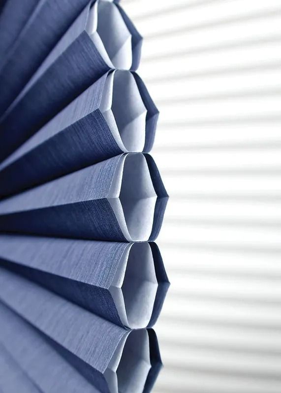 A close up of a blue honeycomb blind on a window.