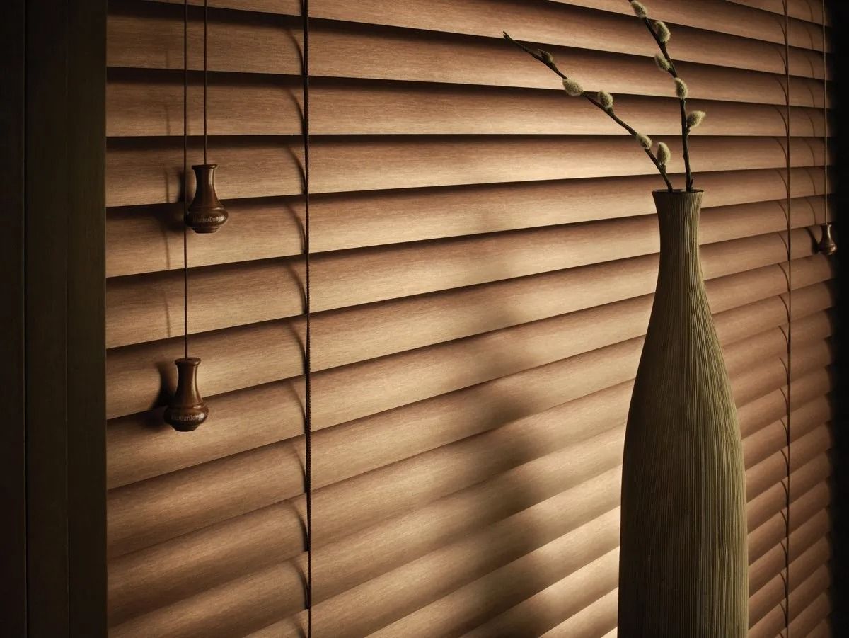 A wooden blind with a vase of flowers hanging from it