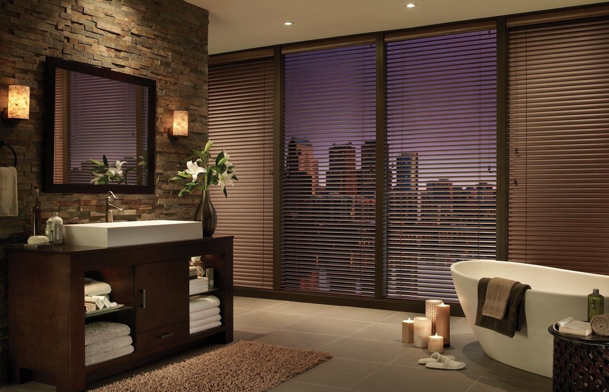 A bathroom with a tub , sink , mirror and blinds.
