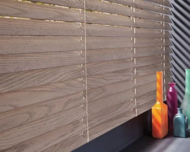 A wooden blind with a few vases in front of it