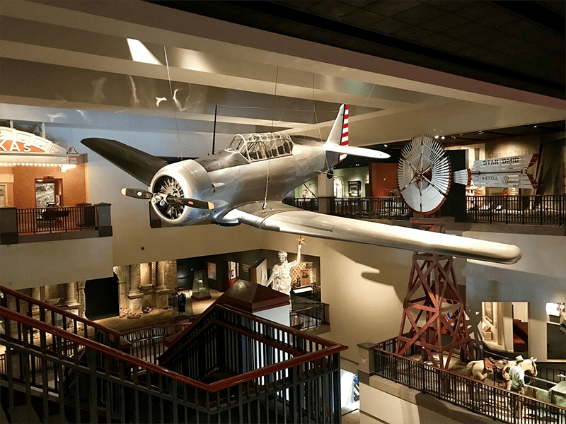 A plane is hanging from the ceiling of a museum.