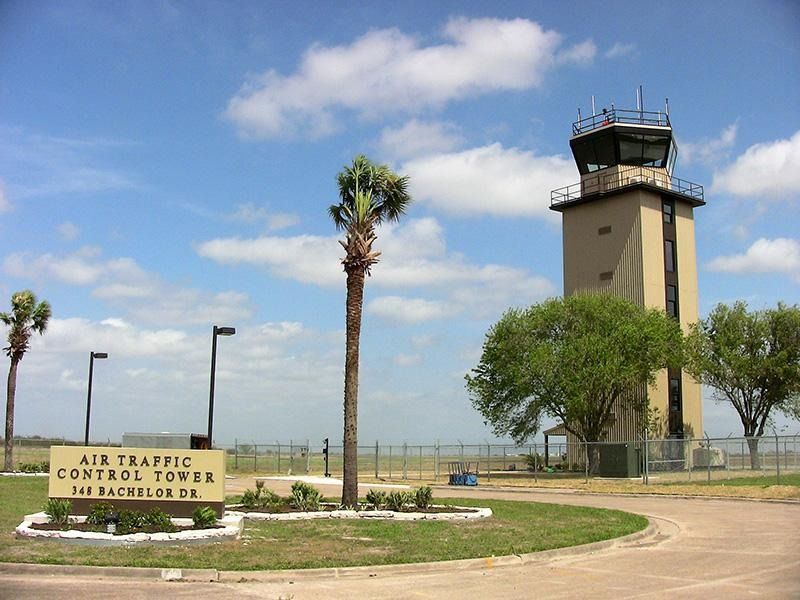 The air traffic control tower is surrounded by palm trees