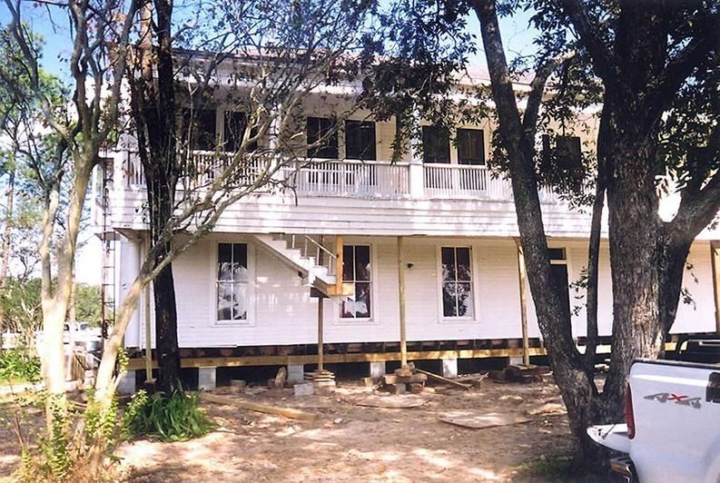 A white truck is parked in front of a white house