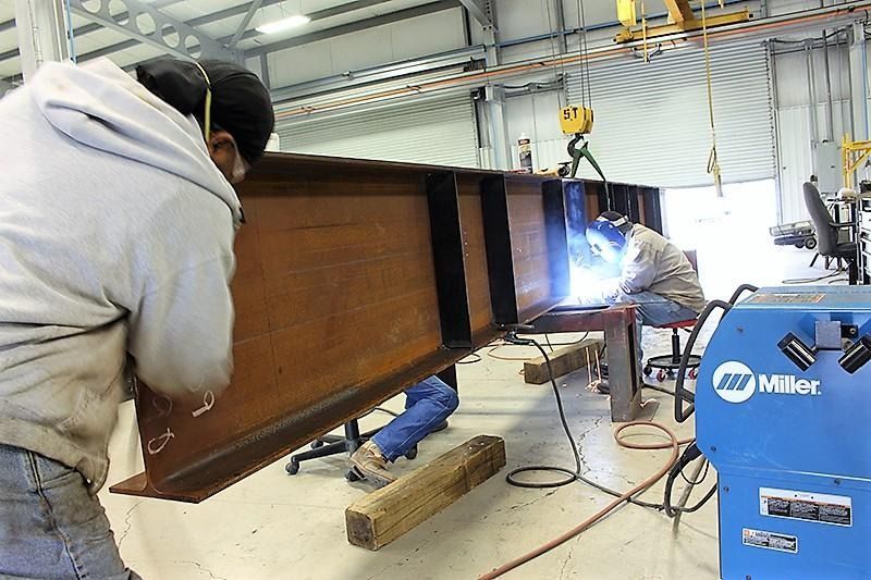A man is welding a large piece of metal in a factory.