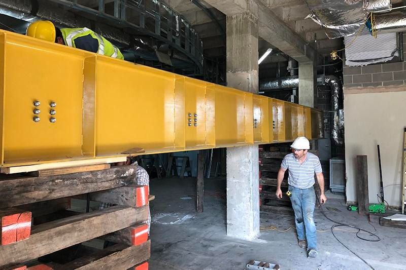 A man wearing a hard hat is walking through a building under construction.