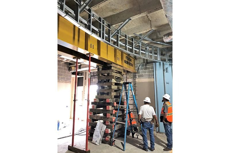 A group of construction workers are standing in a building under construction.