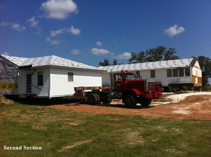 A red truck is carrying a house in the second section
