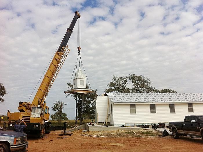A yellow crane is lifting a white building