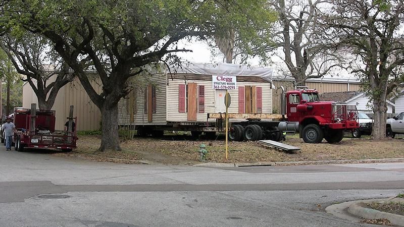 A red truck is carrying a mobile home on a trailer