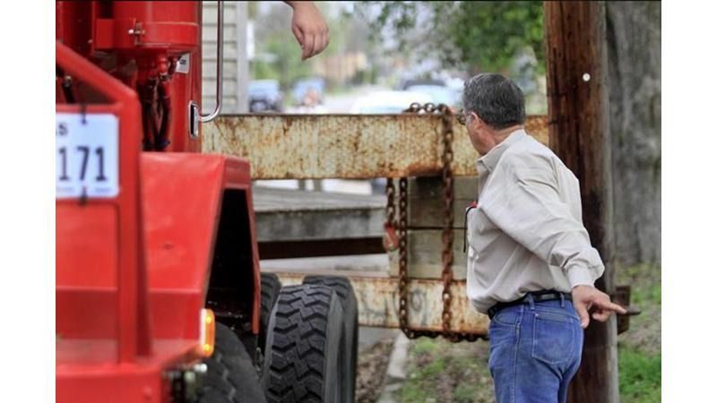 A man standing next to a red truck with a license plate that says 171