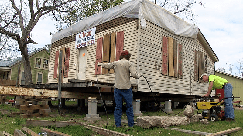 Two men are working on a house that is being moved.