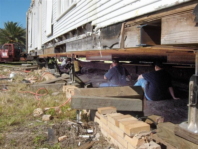 A group of people are sitting under a house that is being moved