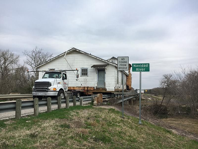 A truck is carrying a house across a bridge.