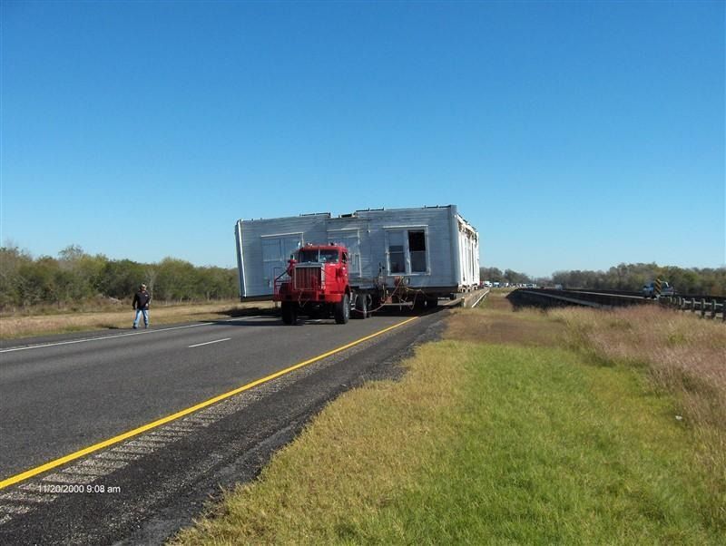 A red truck is pulling a trailer down a highway