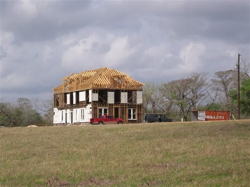 A red truck is parked in front of a house under construction