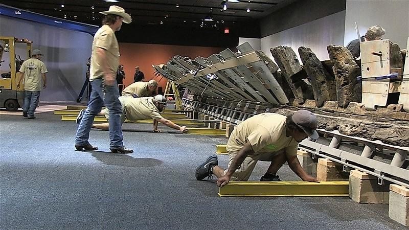 A group of men are working on a large piece of wood